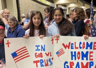 Kids holding "Welcome Home" signs at the airport as veterans return from their Honor Flight trip.